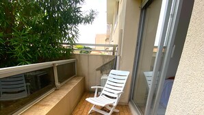 A small balcony with a white chair, tiled floor, and a metal railing.