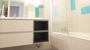 A bathroom with a mirror, sink, and shower.