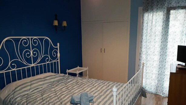 A bedroom with a bed, a nightstand, a wardrobe, and a television. - 2 Bed Flat - Sleeps 4 - Pets - Wifi (Thessaloniki)