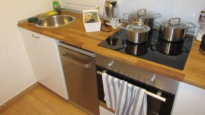 A compact kitchen with a wooden countertop, a sink, a dishwasher, and a stove. - 2 Bed Flat - Sleeps 4 - Pets - Wifi (Thessaloniki)