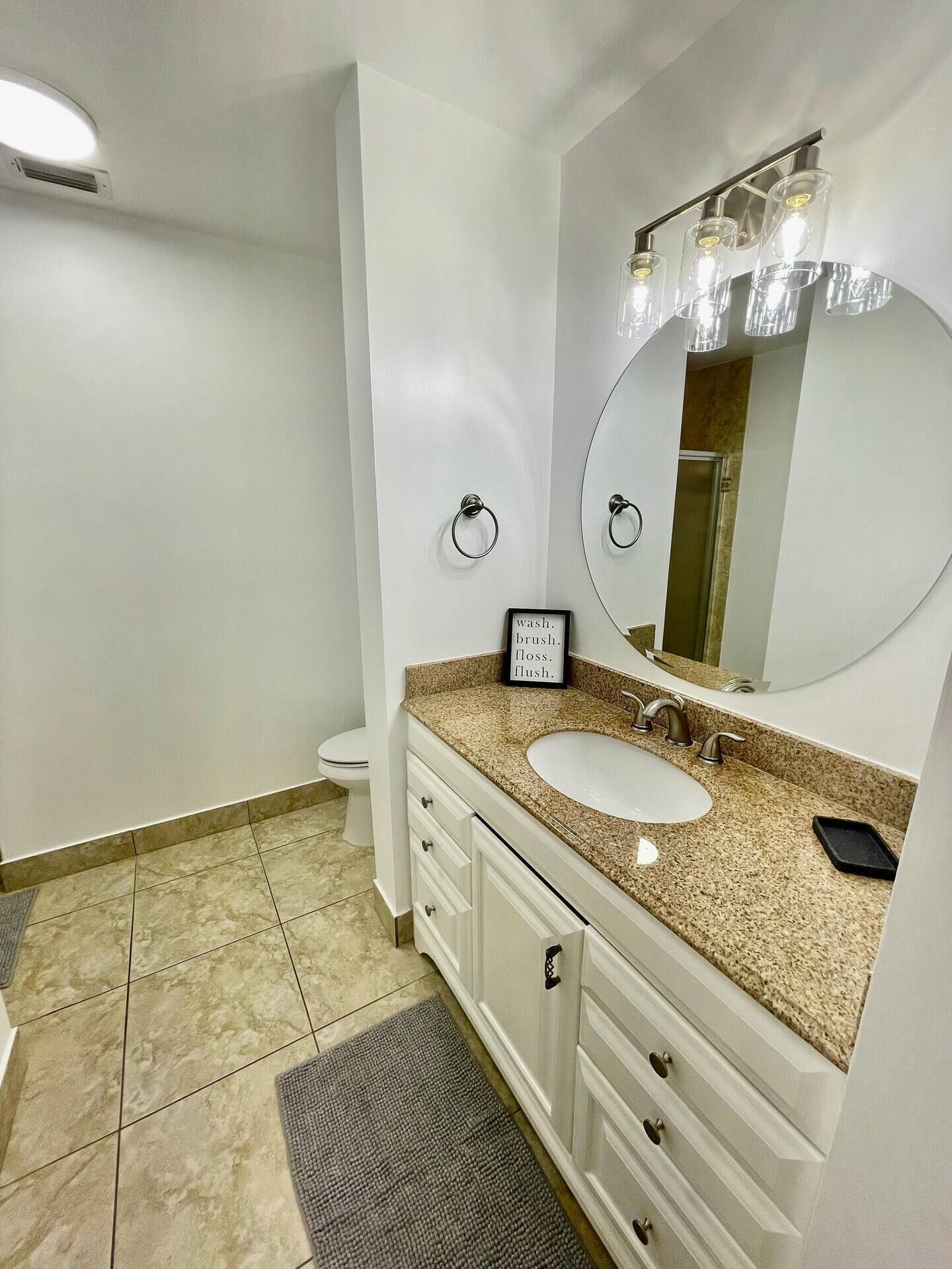 Une salle de bain avec un lavabo blanc, un miroir et un porte-serviette.