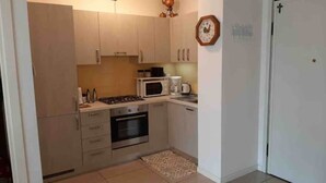 Una cocina compacta equipada con microondas, estufa, horno y cafetera.