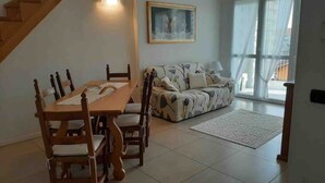 Un comedor con una mesa y sillas de madera, un sofá y un cuadro en la pared.