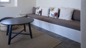 A modern living room with a sofa, a round table, and a hanging light fixture. - Charming Private Greek Heritage Retreat (Tavros) (Mykonos-Town)