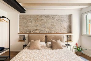 Une chambre avec un lit, un mur en briques, une fenêtre et une plante.