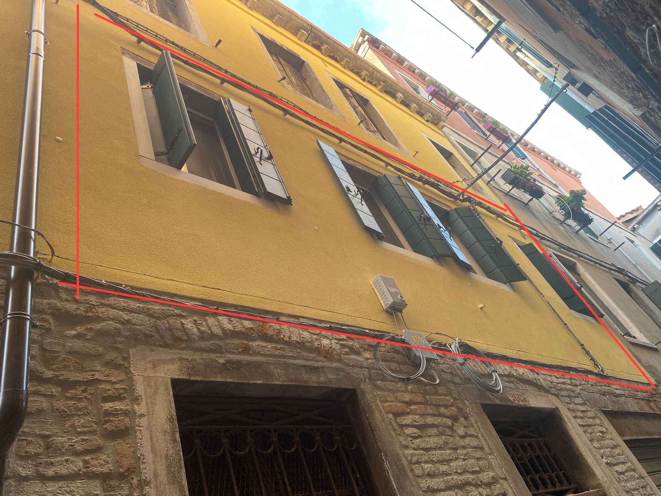 A yellow building with multiple windows and a stone base.