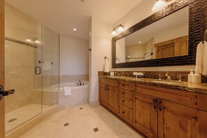 A modern bathroom with a glass-enclosed shower, a freestanding bathtub, wooden cabinetry, and a large mirror with a unique frame. - Luxury Summer Condo by InvitedHome | Walk to Town, Corner Patio Views (Telluride)