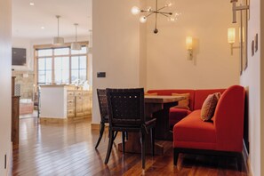 A modern kitchen with wooden cabinets, a dining area with a red sofa and chairs, and a chandelier. - Luxury Summer Condo by InvitedHome | Walk to Town, Corner Patio Views (Telluride)