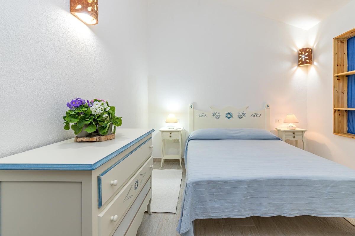 Une chambre à coucher comprenant un lit, des tables de chevet, une commode et des appliques murales.