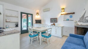 Una cocina moderna con armarios blancos, una mesa de comedor y sillas. Hay un sofá azul en la sala de estar.