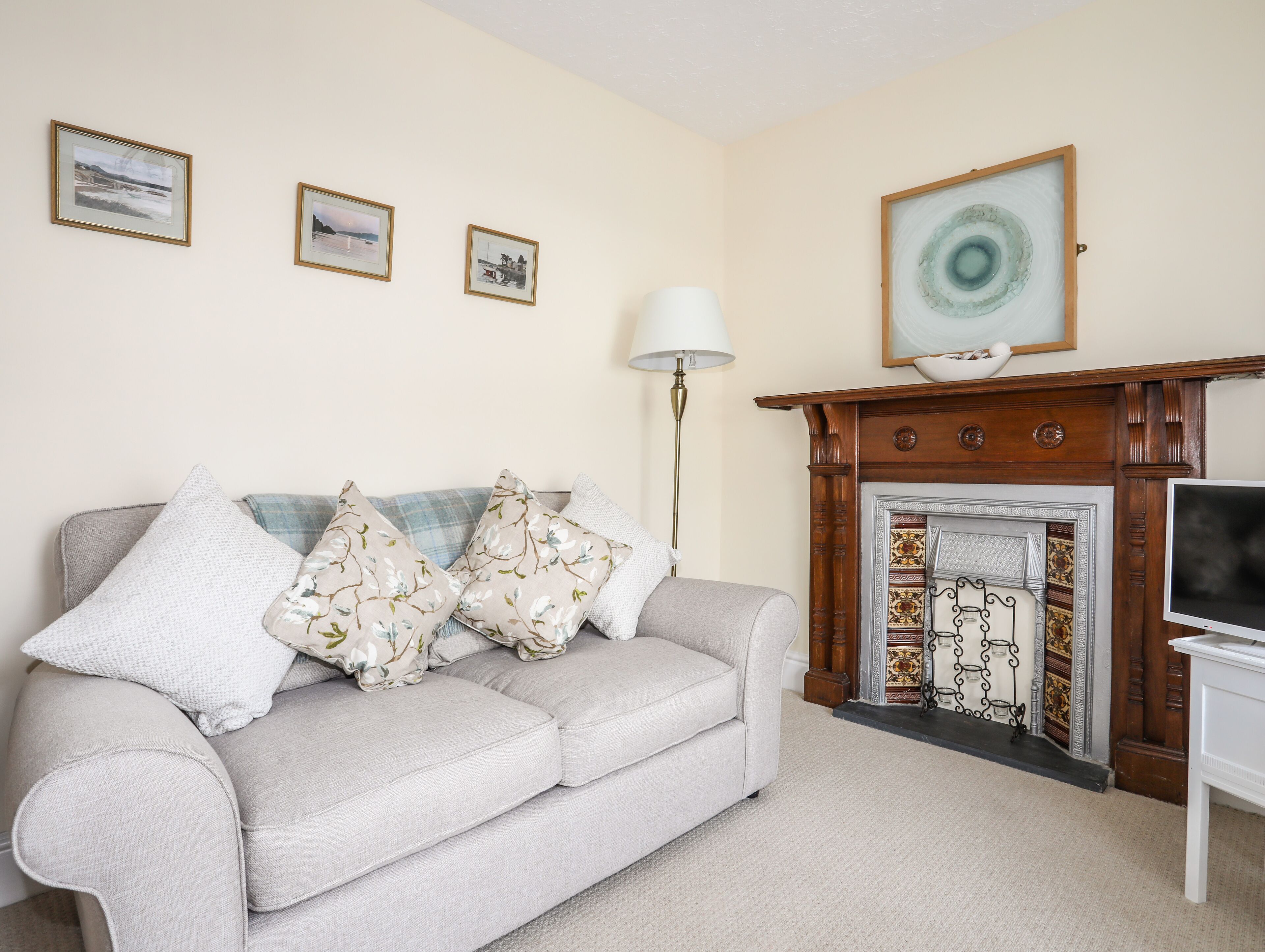 A living room with a sofa, pillows, a lamp, a fireplace, and framed pictures on the wall.