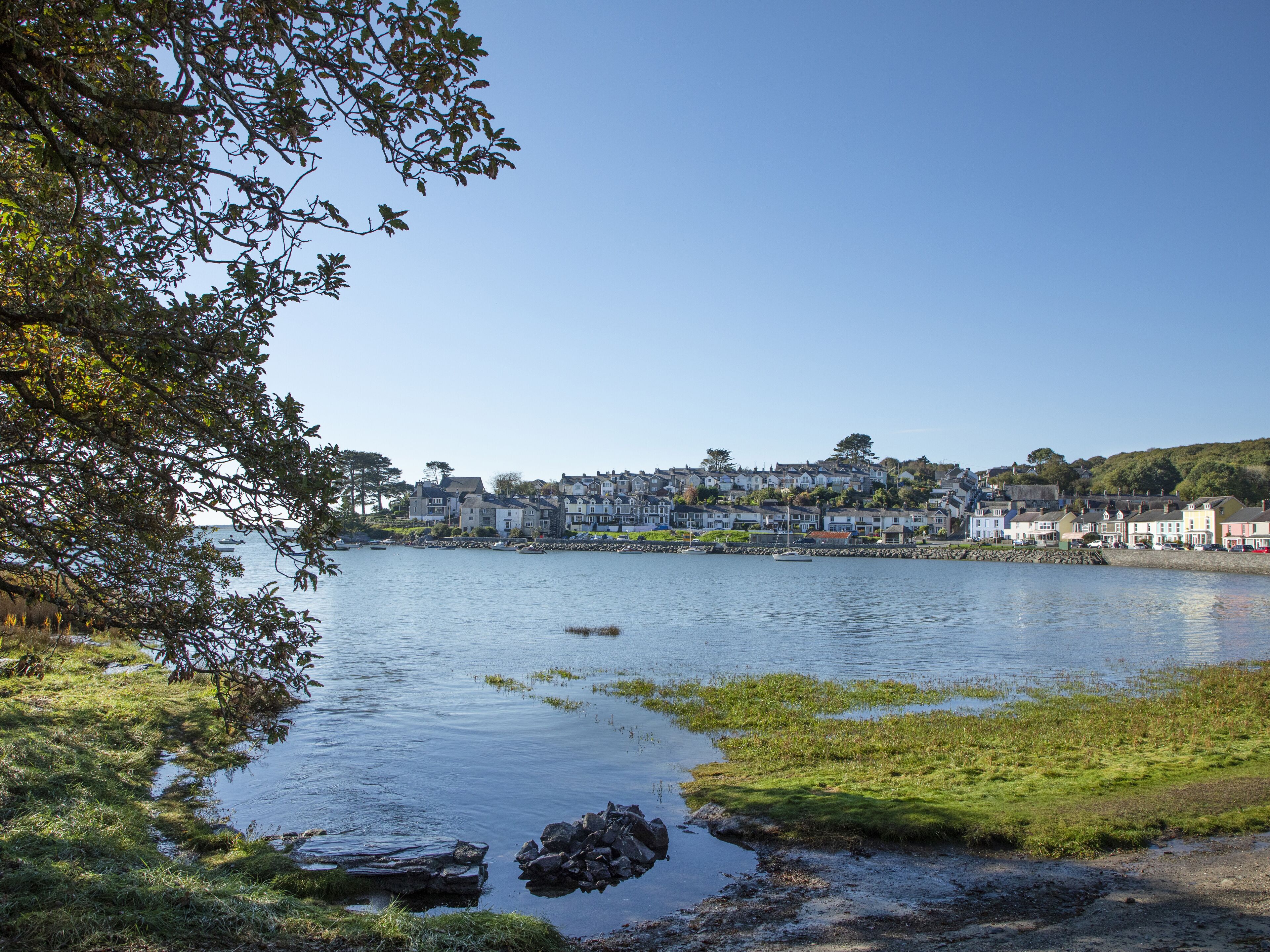 A coastal town with buildings along the water, a clear sky, and a calm sea.