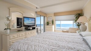 A hotel room with a large bed, a television, a desk, and a view of the ocean. - Direct Oceanfront With a Pool! (Ocean City)