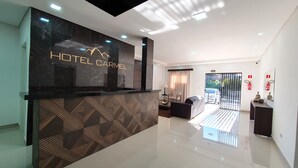 A modern hotel reception area with a marble counter, a patterned wall, and a view of the outside.