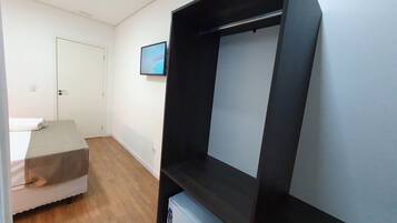 A room with a bed, a small table, a TV on the wall, and a wardrobe.