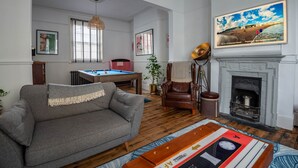 A spacious living room with a grey sofa, a pool table, a fireplace, and a large framed picture on the wall. - The Broadstairs Townhouse (Broadstairs)