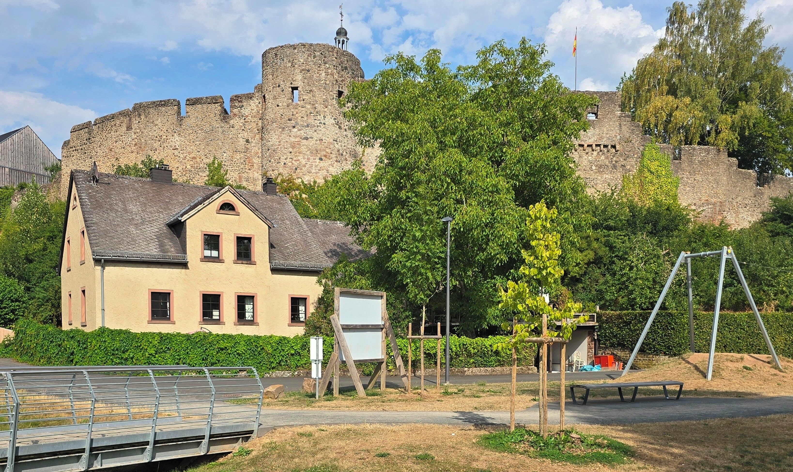 Un château de pierre historique, avec une maison traditionnelle en premier plan.