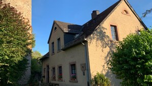 Une maison à deux étages avec une tour en pierre, un toit en pente et un petit balcon.