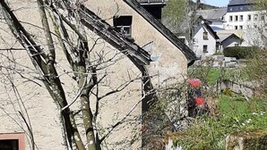 Un bâtiment en pierre avec un toit en pente, une fenêtre et une cheminée. Devant le bâtiment, on aperçoit un arbre aux branches nues.
