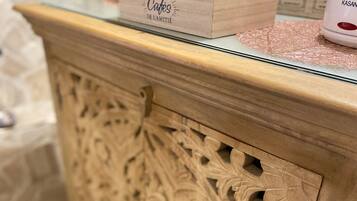 Een houten kast met ingewikkelde houtsnijwerken, een doosje met de tekst 'Les Petits Cafés de L'amitié' en een wit object erboven.