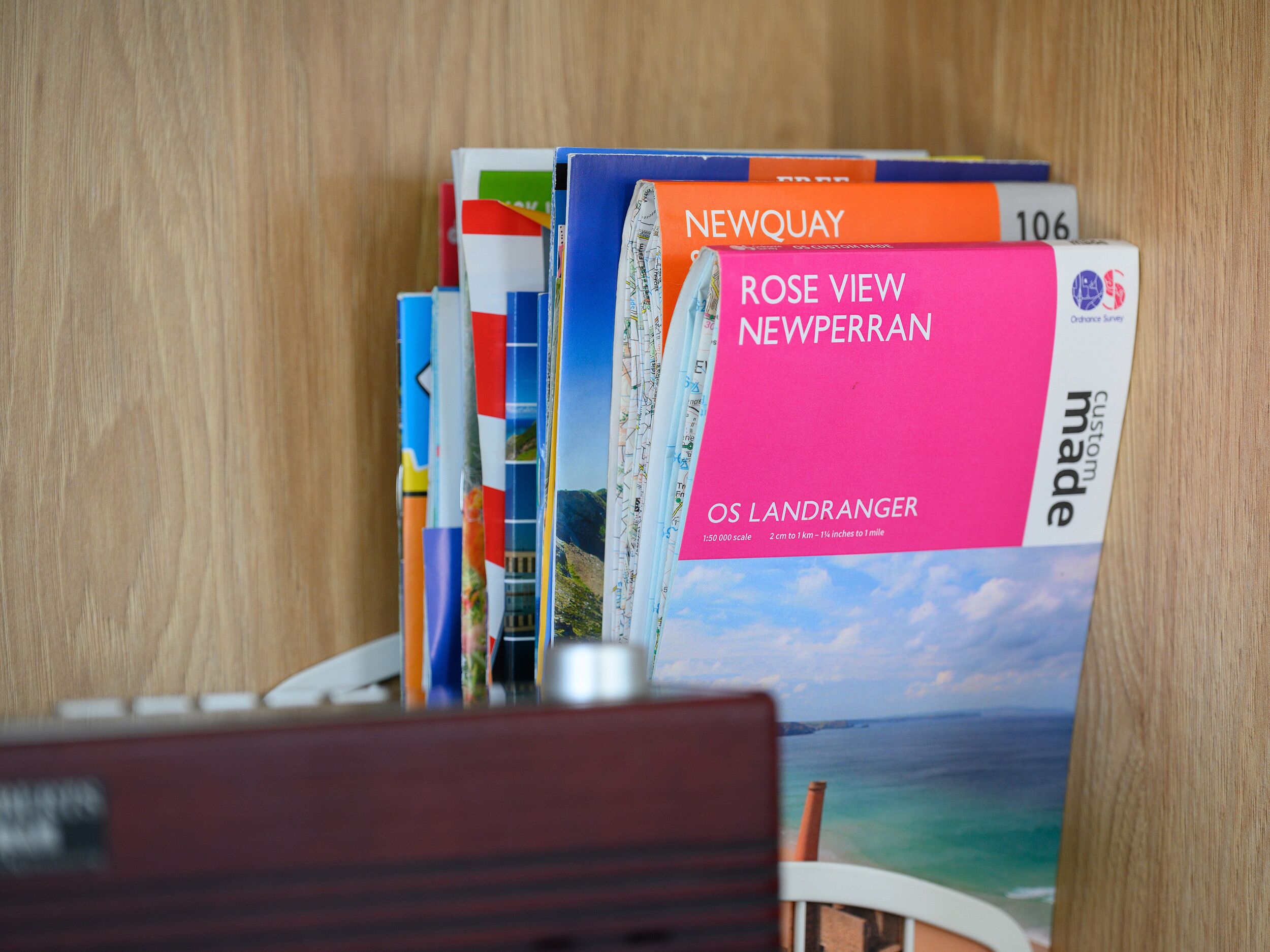 A bookshelf with various books, including titles like 'Newquay' and 'Rose View Newperran'.