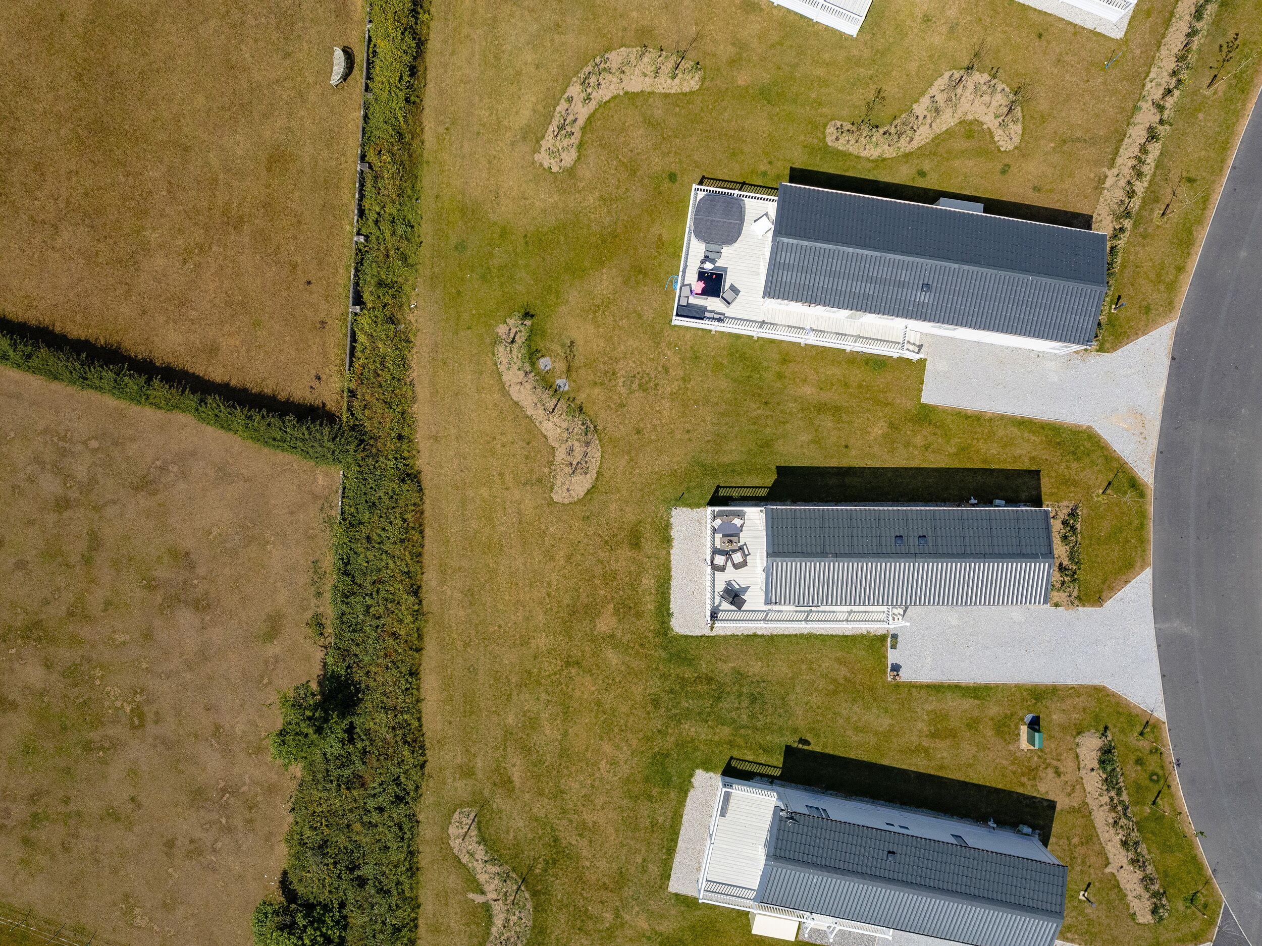 An aerial view of a property with two buildings, a parking area, and surrounding grassy fields.