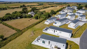 Um conjunto de casas móveis com varandas, situado numa área rural com campos abertos e céu limpo.