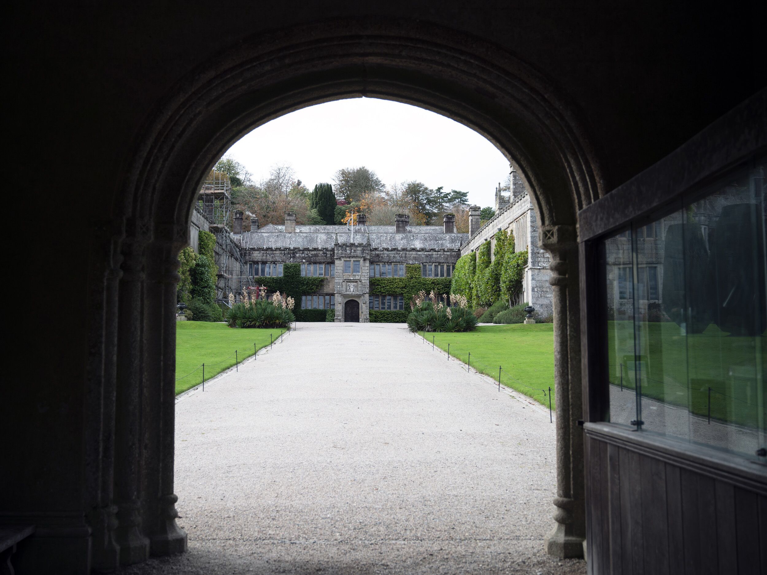 An arched entrance leading to a courtyard with a building in the background.