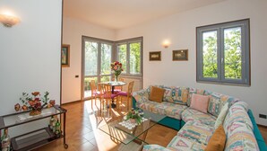 Un salón amplio con sofá, una mesa de centro de vidrio y un comedor con sillas y una mesa.