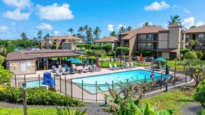 A resort with a swimming pool, sun loungers, and a covered seating area. - Unbeatable Ocean Front Condo  Pono Kai Resort C302 (Kapa'a)