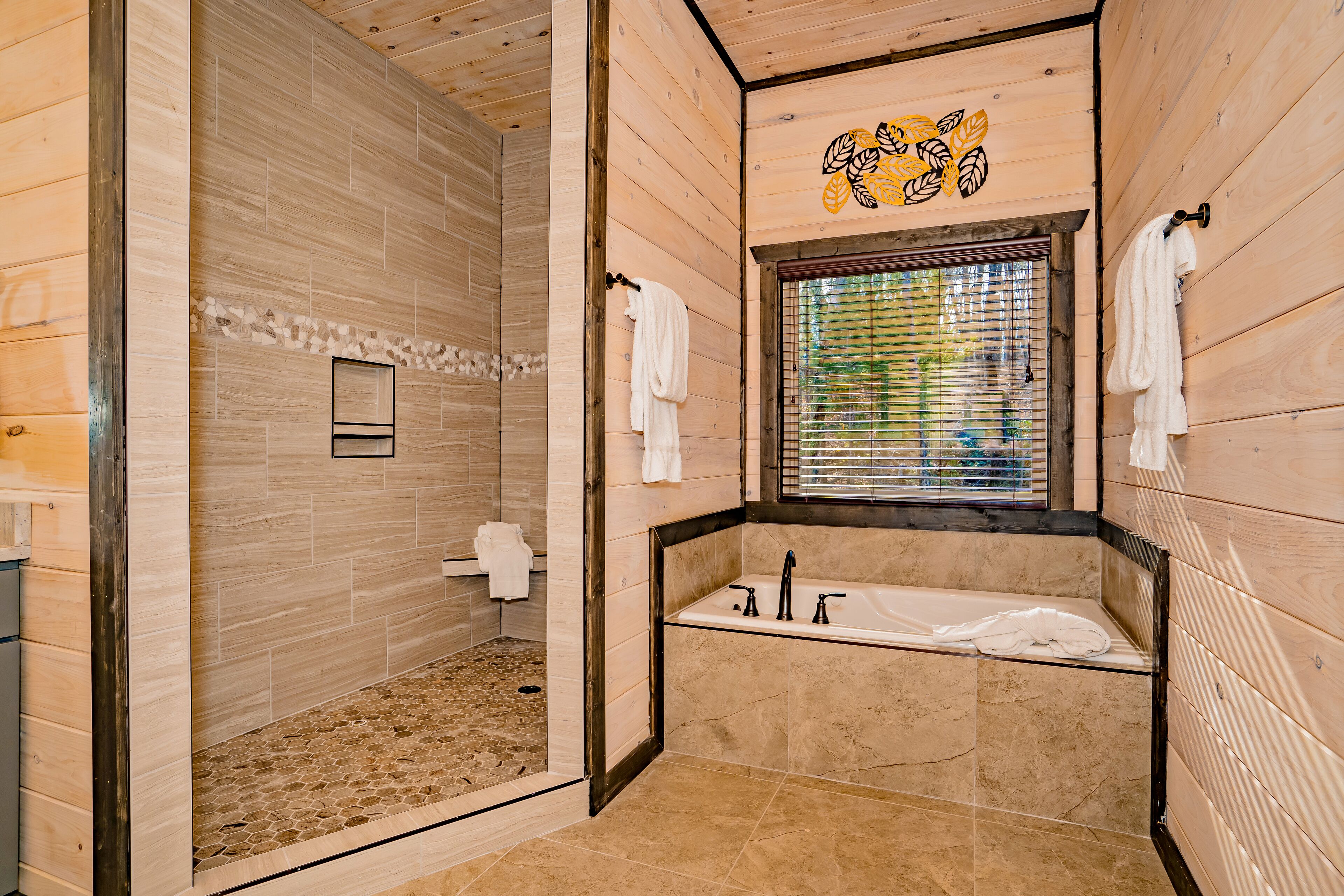 Un baño de madera con ducha, bañera y ventana con persianas.