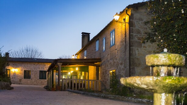 A stone building with a covered entrance and a fountain in the foreground. - Large villa with pool near Santiago (Ames)