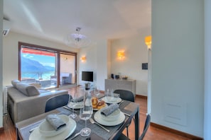 Un comedor con una mesa lista para dos personas, un sofá y vistas al exterior.