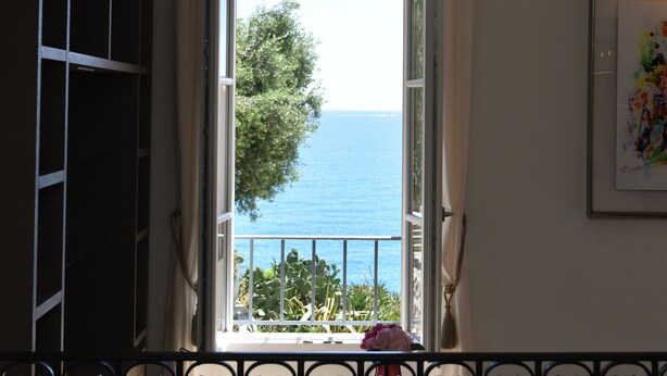Ein Zimmer mit Meerblick, ein Balkon mit Geländer und ein Tisch mit einer Vase.