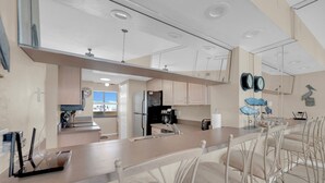 Une cuisine moderne dotée d’un îlot central, d’appareils électroménagers en acier inoxydable et offrant une vue sur l’extérieur.