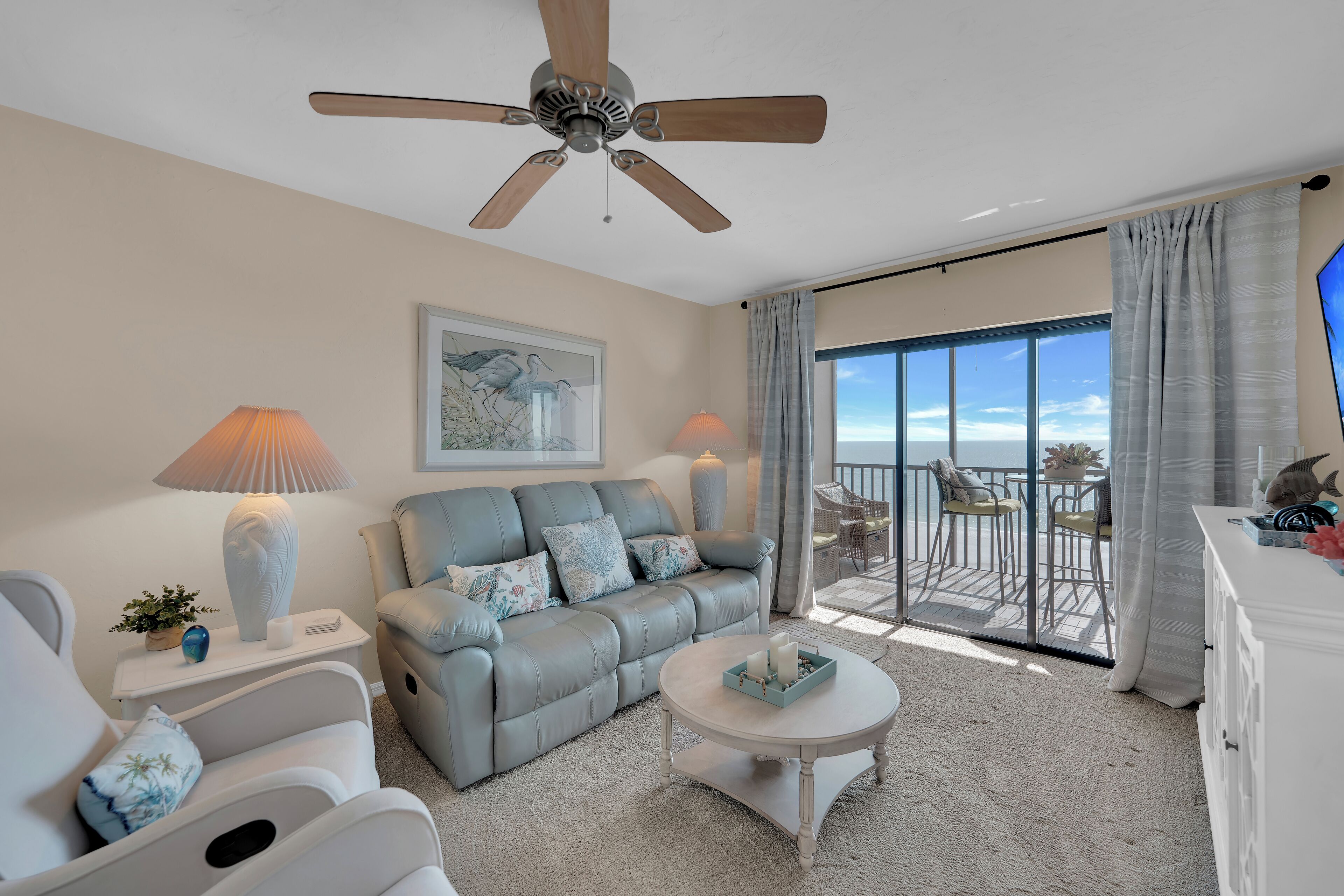 A living room with a grey sofa, a white coffee table, and a ceiling fan.