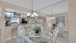 Un espace repas moderne avec une table en verre, des chaises blanches et un arrangement floral central.