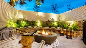 Une terrasse extérieure dotée d’un foyer, de sièges en pierre et de lanternes.