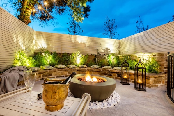 An outdoor patio with a fire pit, stone seating, and lanterns.