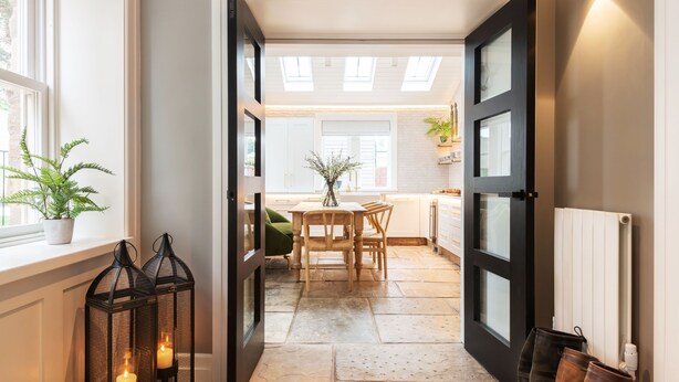 Une cuisine moderne avec un coin repas, dotée d’une lucarne, d’un plan de travail blanc et d’une plante en pot.