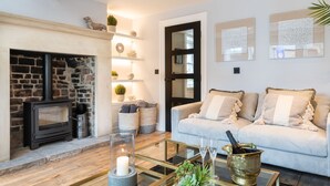 Un salon chaleureux avec une cheminée en pierre, une table basse en verre et un canapé confortable.