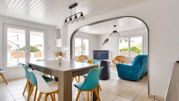Un coin repas avec une table et des chaises en bois, un téléviseur et un fauteuil bleu.