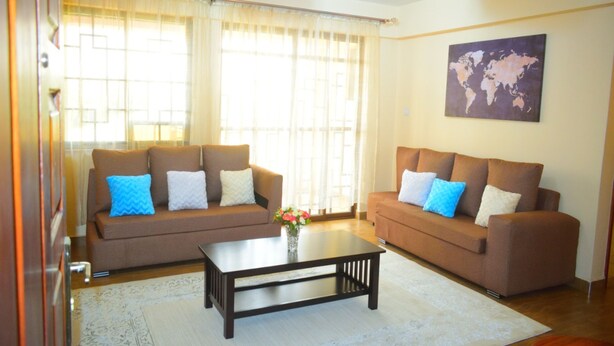 A living room with two brown sofas, a coffee table, and a world map on the wall. - Mukoma Heights (Nairobi)