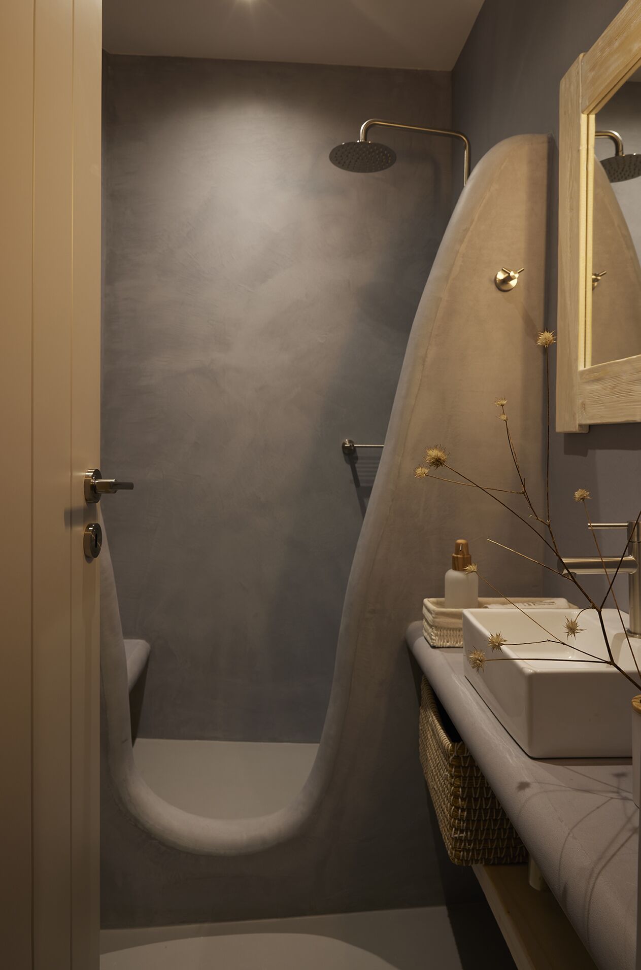 A modern bathroom with a grey shower, a white sink, and a mirror.