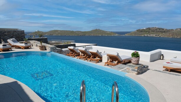A pool area with lounge chairs and a view of the sea. - KEA MARE LUXURY VILLAS (Kea)
