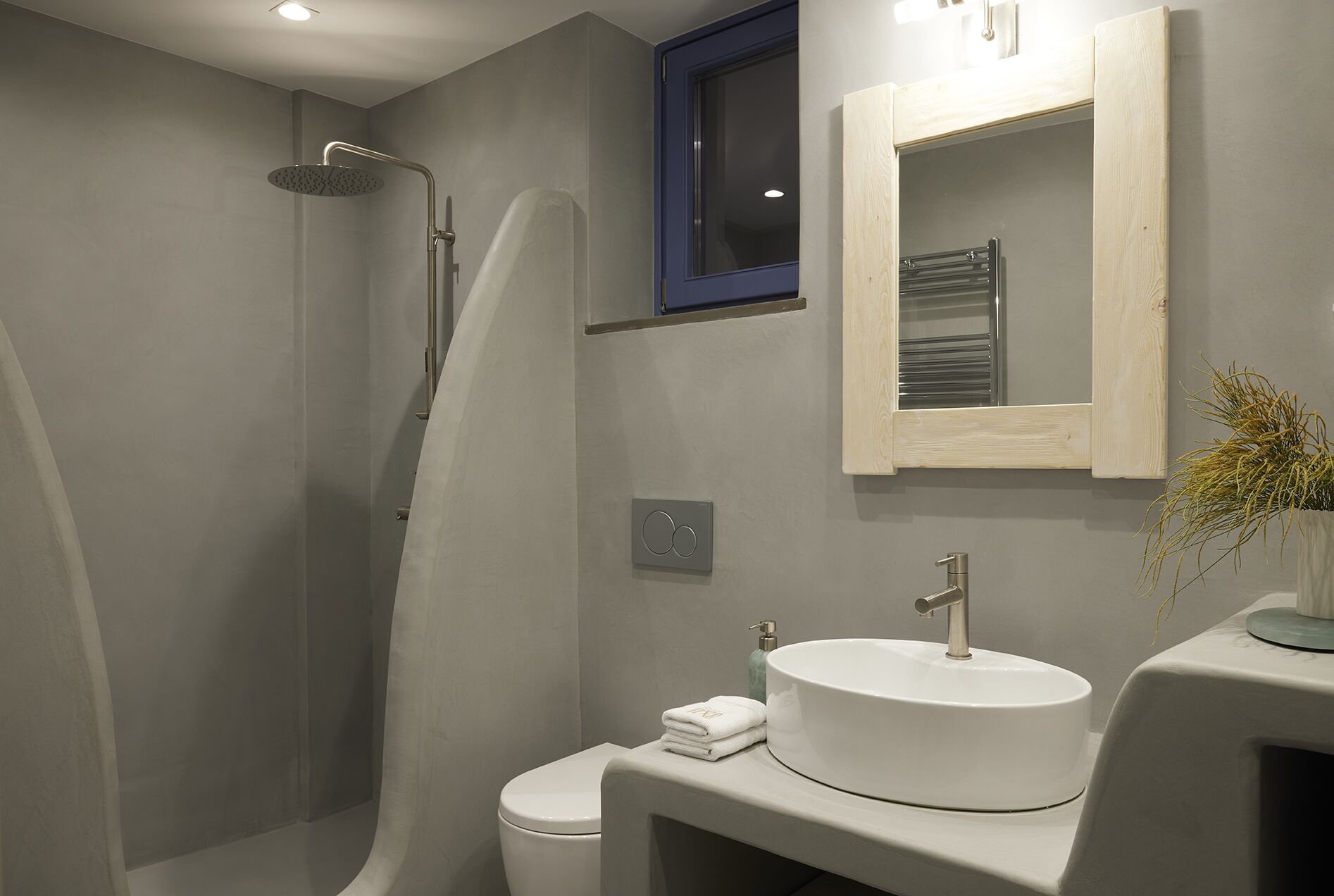 A modern bathroom with a walk-in shower, a toilet, a sink, and a mirror.