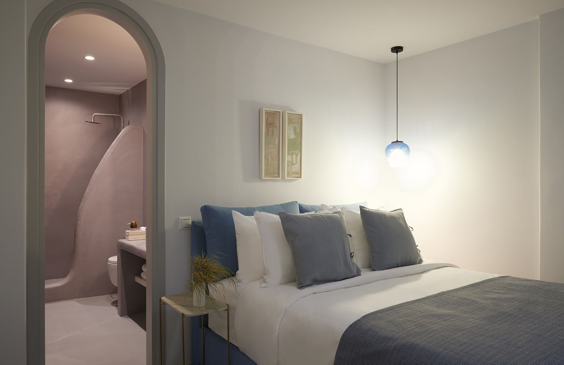A modern bedroom with a bed, bedside table, and a hanging light fixture.
