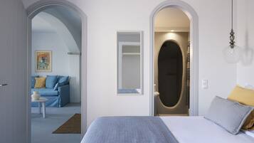 A bedroom with a bed, a bedside table, a mirror, and an arched doorway leading to a bathroom.