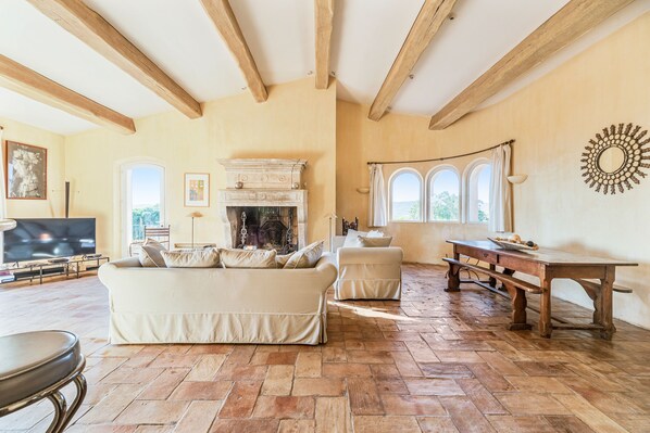 A living room with a fireplace, a sofa, a table, and a TV.