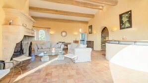 A spacious living room with a fireplace, two sofas, a coffee table, and a stone-tiled floor. - St Tropez, large park, unbelievable view sea-forests-hills, 8 bedroom, pool 65ft (Ramatuelle)